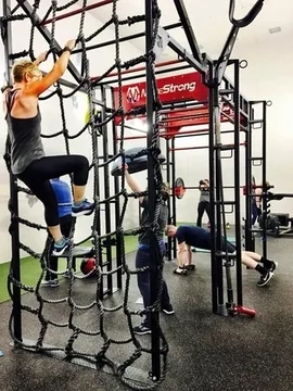 Member climbing a cargo net in the Rig Room functional training area at Falmouth Sports Center